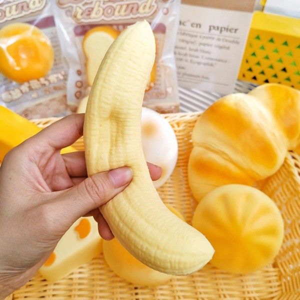This banana squishy toy is a fun, fruity novelty that customers reach for on sight. Molded in a realistic curved fruit shape, it is crafted from soft slow-rise foam with a smooth, lifelike finish. Lightweight and pocket-sized, it makes a perfect stress reliever, fidget toy, or playful gift. A natural fit for fruit-themed gift sections, toy boutiques, and impulse buy displays near checkout. Easy to merchandise on a peg hook or in a bowl display — a reliable sell-through item.