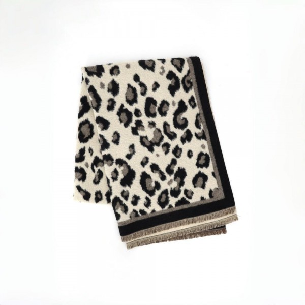 Animal print scarf in a soft brushed weave with a solid contrast border and knotted fringe ends. Long wrap length loops twice or drapes open over a coat, and the spotted print carries a neutral outfit on its own. A cold weather staple for boutique buyers stocking travel, tailgates, farmers markets, and holiday gifting. Animal print scarves are a proven repeat seller that never sits on the rack.