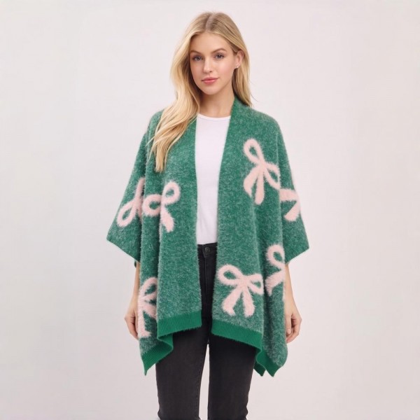 Bow Print Knit Ruana Poncho with an open-front drape and generously oversized fit. The double-sided jacquard knit showcases a whimsical allover bow motif with contrast edging — an easy one-size topper that layers beautifully over basics for an instant outfit. A playful statement piece with strong gift appeal that stands out on boutique racks and social feeds alike.