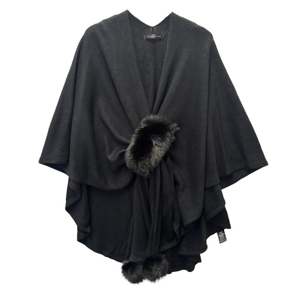Knit cape wrap finished with faux fur pom ties at the front, cut wide through the shoulder and falling past the hip. The brushed yarn feels substantial without weighing a shoulder down, and the open silhouette layers over tees, turtlenecks, and slim knits. One forgiving size covers a wide customer range, which keeps buying simple. A high impact rack piece that lifts the average ticket through fall and holiday.