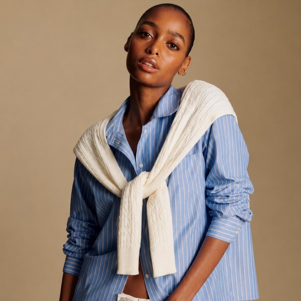 Cable Knit Sweater Shoulder Wrap that recreates the classic sweater over the shoulders look without the bulk of a full pullover. Soft cable knit sleeves tie loosely at the chest for an effortless, preppy finish over button downs, tees, and dresses. Perfect for cool fall mornings, country club brunches, football tailgates, and travel days. This trending layering piece is a quick seller that boutique shoppers love to style and gift.