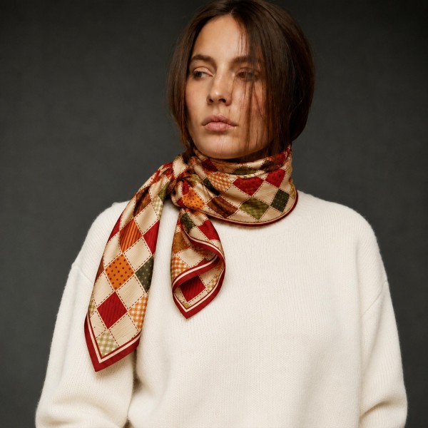 Harlequin Check Silky Square Scarf with a patchwork diamond pattern of gingham, dots, and solid blocks finished with a striped border. The soft satin feel ties neatly at the neck, drapes over a coat, or adds a pop to a handbag or ponytail. A charming pick for fall festivals, coffee dates, teacher outfits, and holiday gatherings. Vintage inspired patchwork prints are a trending look that shoppers love to layer with knits and denim.