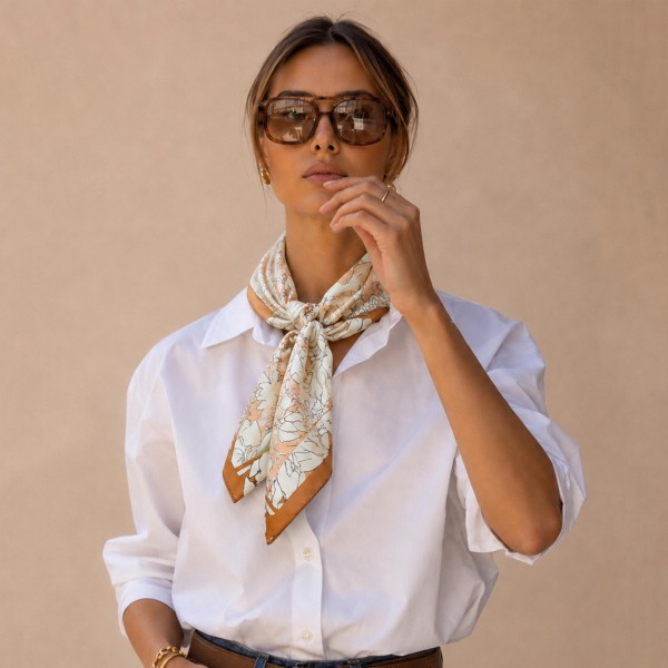 Botanical print square scarf in a soft satin-feel woven, with hand-drawn florals and foliage framed by a contrast border. Roomy enough to knot at the neck, fold into a triangle over a jacket, or tie onto a tote handle, and light enough to layer without bulk. The illustrated botanical motif is a boutique staple that carries from early fall straight through the holidays. An easy add-on sale that keeps the accessory wall looking full.