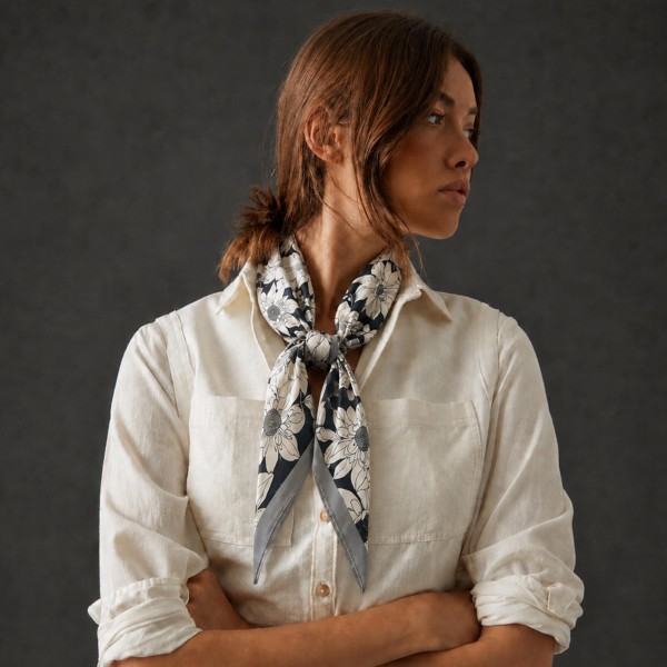 Botanical print square scarf in a soft satin-feel woven, with hand-drawn florals and foliage framed by a contrast border. Roomy enough to knot at the neck, fold into a triangle over a jacket, or tie onto a tote handle, and light enough to layer without bulk. The illustrated botanical motif is a boutique staple that carries from early fall straight through the holidays. An easy add-on sale that keeps the accessory wall looking full.