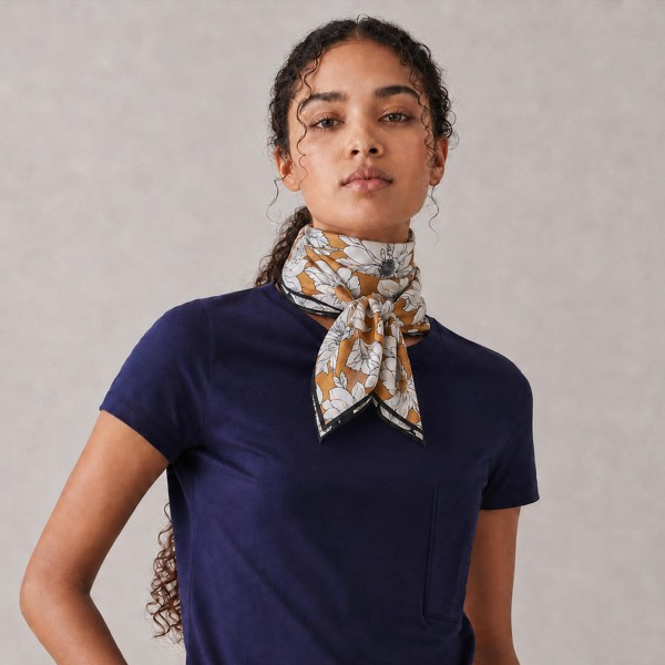 Botanical print square scarf in a soft satin-feel woven, with hand-drawn florals and foliage framed by a contrast border. Roomy enough to knot at the neck, fold into a triangle over a jacket, or tie onto a tote handle, and light enough to layer without bulk. The illustrated botanical motif is a boutique staple that carries from early fall straight through the holidays. An easy add-on sale that keeps the accessory wall looking full.
