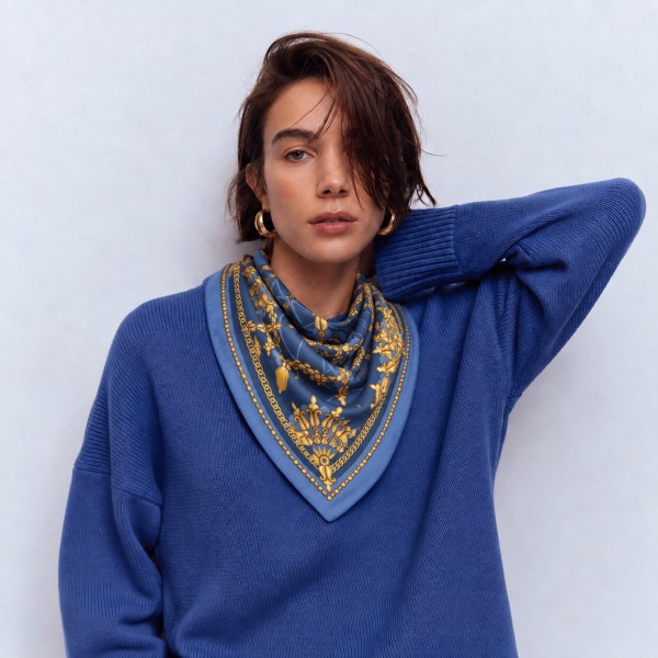 Chain and tassel print square scarf in a lightweight satin-feel woven, with an ornate link motif and a framing border. The generous square drapes over the shoulders like a shawl, folds into a neck knot, or ties onto a handbag for an instant lift. Status chain prints give a display an elevated, designer-inspired look at an impulse price point. A strong transitional piece that carries from early fall into holiday.