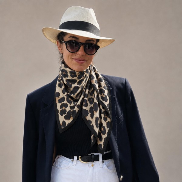 Oversized leopard print square scarf in a soft satin-feel woven with a fine framing border. The larger square drapes as a shoulder wrap, folds into a full triangle over a jacket, or knots at the neck for a polished finish. Animal print is a reliable fall repeat purchase that works with everything already on the floor. High impact on a display rack at an easy impulse price.