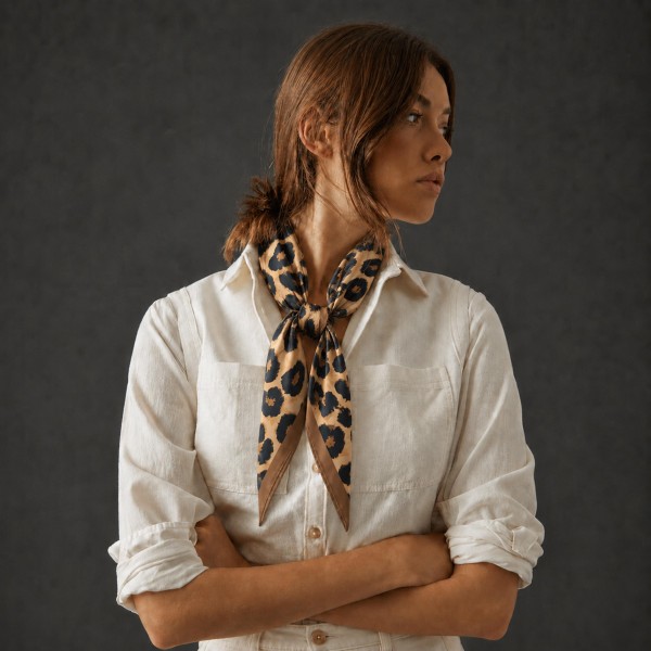 Oversized leopard print square scarf in a soft satin-feel woven with a fine framing border. The larger square drapes as a shoulder wrap, folds into a full triangle over a jacket, or knots at the neck for a polished finish. Animal print is a reliable fall repeat purchase that works with everything already on the floor. High impact on a display rack at an easy impulse price.