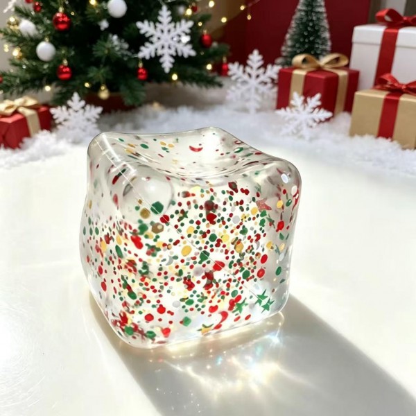 Confetti cube squishy filled with tiny holiday flecks suspended in a clear jelly block that catches the light from every angle. The soft body flattens under a squeeze and drifts back into a cube shape. A quiet fidget that looks like decor when it is sitting out on a desk or a shelf. Seasonal sparkle at an impulse price point.