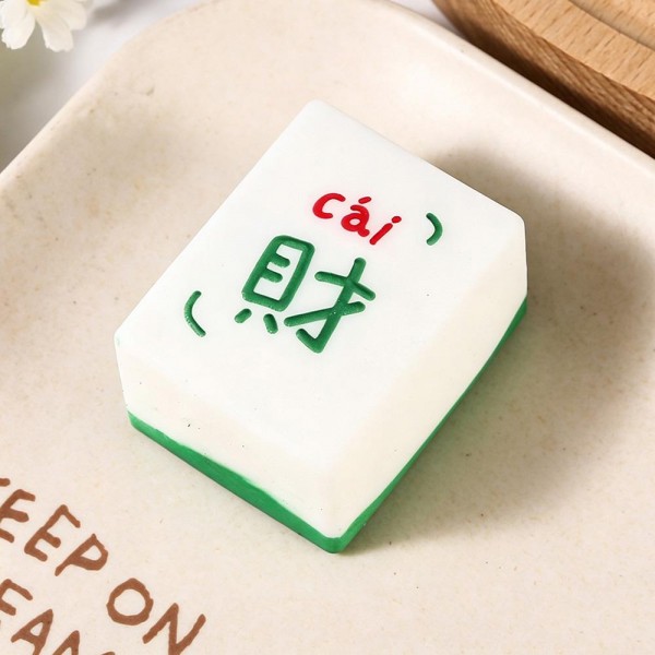 Mahjong tile squishy molded as a full size game tile with a raised painted character and a colored base edge. Slow rise foam compresses under a squeeze and slowly returns to shape for repeat fidgeting. A counter impulse toy for boutiques stocking game night gifts, classroom rewards, desk toys, and stocking stuffers. Game tile squishies pull a second look on a display riser and ring up as an easy add on.
