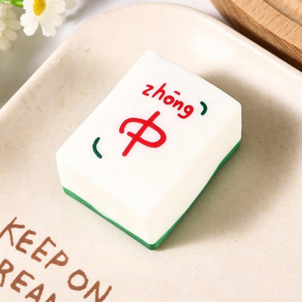 Mahjong tile squishy molded as a full size game tile with a raised painted character and a colored base edge. Slow rise foam compresses under a squeeze and slowly returns to shape for repeat fidgeting. A counter impulse toy for boutiques stocking game night gifts, classroom rewards, desk toys, and stocking stuffers. Game tile squishies pull a second look on a display riser and ring up as an easy add on.