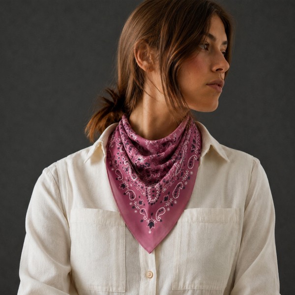 Paisley Bandana Print Square Scarf in silky 100% polyester, measuring 27.5 inches square. A classic bandana layout pairs a detailed paisley border with a medallion center. Knot it at the neck, wear it as a headscarf, or tie it onto a bag handle for an easy, laid back touch. A timeless print that layers well over sweaters and jackets, it is a dependable seller in every season.