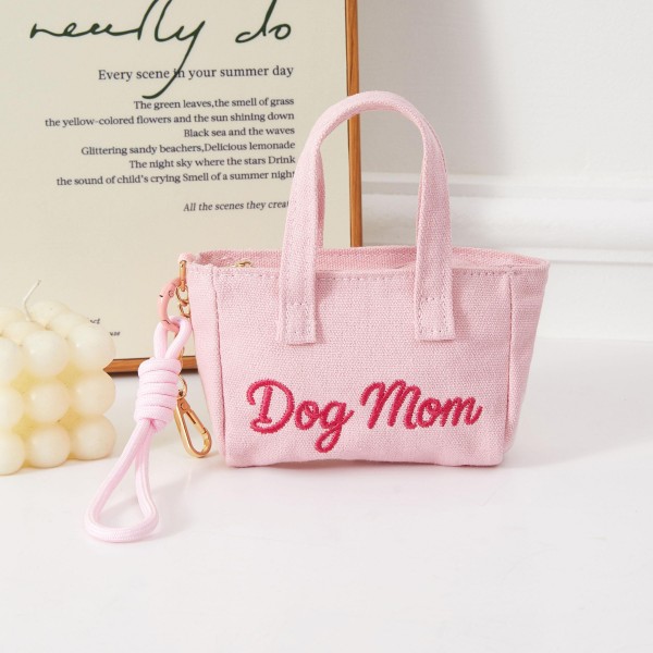 A compact structured mini handbag featuring a playful 'Dog Mom' embroidered script, complete with a removable wrist strap for hands-free convenience. The novelty sentiment taps directly into pet lover culture, making it an instant conversation piece and reliable gift item. Lightweight and easy to merchandise, it sells quickly as an impulse buy near register displays or pet-themed product groupings. A must-stock for boutiques serving the growing market of dog-loving lifestyle shoppers.