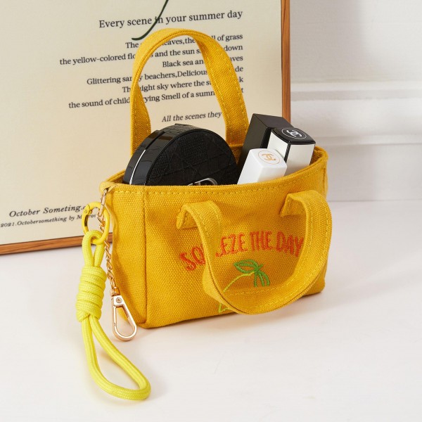 A cheerful structured mini handbag featuring a 'Squeeze the Day' lemon embroidery, complete with a removable wrist strap for on-the-go carry. The fun citrus motif and boxy silhouette make it a natural fit for spring and summer boutique floors. Lightweight and compact, it pairs effortlessly with seasonal apparel and works equally well as a day bag or novelty gift. A quick-selling impulse buy that brightens any accessories display with optimistic, fruit-forward style.