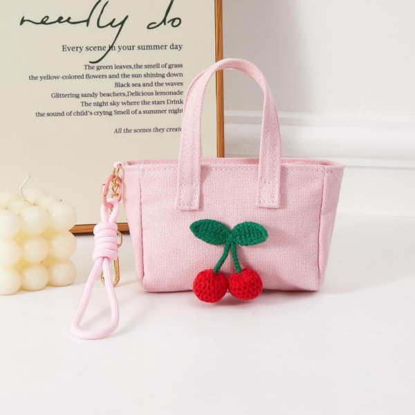 A sweet structured mini handbag accented with a decorative cherry charm for an extra dose of whimsy. The compact boxy design pairs top handles with a removable wrist strap for versatile everyday carry. This fruit-themed accessory taps into a perennially popular motif — ideal for boutiques capitalizing on cherry and fruit-print trend momentum. A charming impulse buy that appeals to shoppers who love feminine novelty accessories with standout detail.