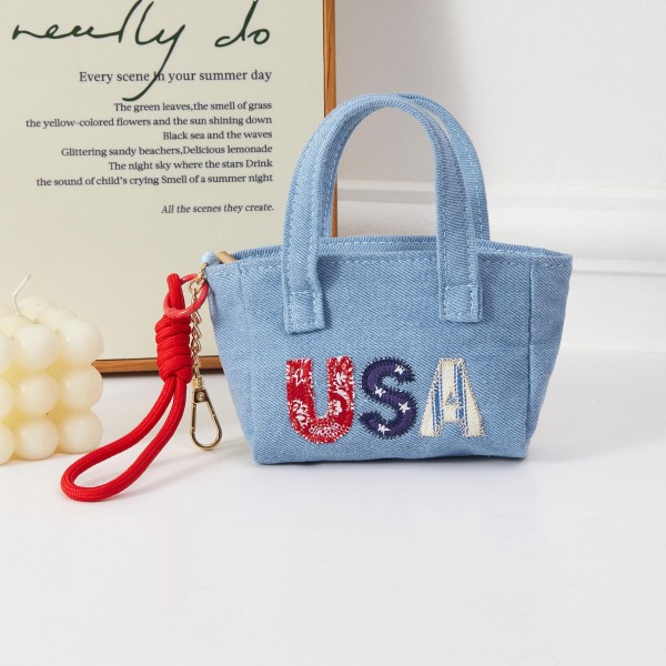 A compact structured mini handbag in denim fabric featuring bold 'USA' embroidery in patriotic lettering, with a removable wrist strap for versatile everyday styling. The boxy silhouette and strong graphic design make this an ideal seasonal accessory for summer holidays. Boutique-friendly and easy to merchandise, it pairs naturally with Americana-themed apparel and accessories. A proven impulse buy that performs consistently during Fourth of July and Memorial Day selling windows.