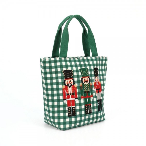 Gingham canvas tote with an embroidered nutcracker trio and contrast webbing handles. Roomy open top carries a wrapped gift, a bottle of wine, or a stack of cookies to the party, and the flat base keeps it upright on a counter. A seasonal carry for boutique buyers stocking hostess gifts, teacher gifts, cookie exchanges, and holiday markets. Embroidered gingham totes double as the gift and the wrapping, which is why they sell out every December.