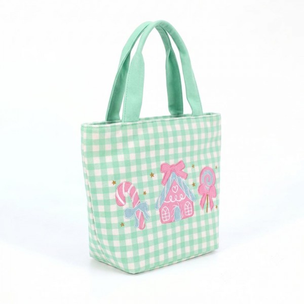 Gingham canvas tote with an embroidered candy house and lollipop scene and contrast webbing handles. Roomy open top carries a wrapped gift, a bottle of wine, or a stack of cookies, and the flat base keeps it upright on a counter. A seasonal carry for boutique buyers stocking hostess gifts, teacher gifts, cookie exchanges, and holiday markets. Embroidered gingham totes double as the gift and the wrapping, which is why they sell out every December.