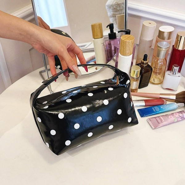 Coated polka dot cosmetic bag with a wide curved zip opening and a soft structured body that keeps its shape when full. Deep enough to stand brushes upright with room left for bottles laid flat. The wipe clean shell shrugs off powder and spills, so it still looks new after a season of daily use. A pretty, practical piece that sells on its own and sells better beside a matching tote.