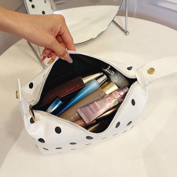 Coated polka dot cosmetic bag with a wide curved zip opening and a soft structured body that keeps its shape when full. Deep enough to stand brushes upright with room left for bottles laid flat. The wipe clean shell shrugs off powder and spills, so it still looks new after a season of daily use. A pretty, practical piece that sells on its own and sells better beside a matching tote.