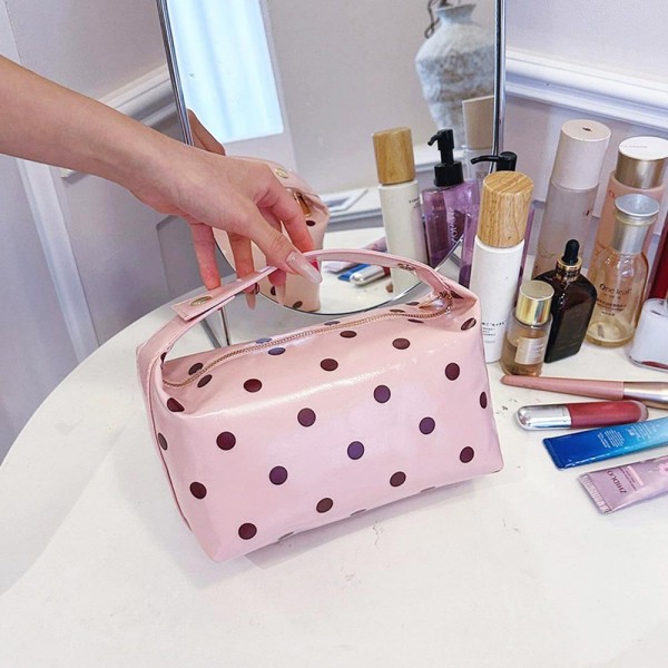 Coated polka dot cosmetic bag with a wide curved zip opening and a soft structured body that keeps its shape when full. Deep enough to stand brushes upright with room left for bottles laid flat. The wipe clean shell shrugs off powder and spills, so it still looks new after a season of daily use. A pretty, practical piece that sells on its own and sells better beside a matching tote.