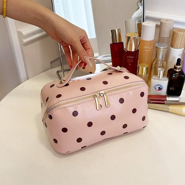 Wide opening makeup case that unzips almost fully so everything lies flat and visible instead of buried at the bottom. A padded body protects glass bottles and pressed compacts, and the short top handle makes it easy to move from counter to suitcase. The coated polka dot exterior wipes clean with a damp cloth. An everyday travel piece priced for repeat purchase and easy gifting.