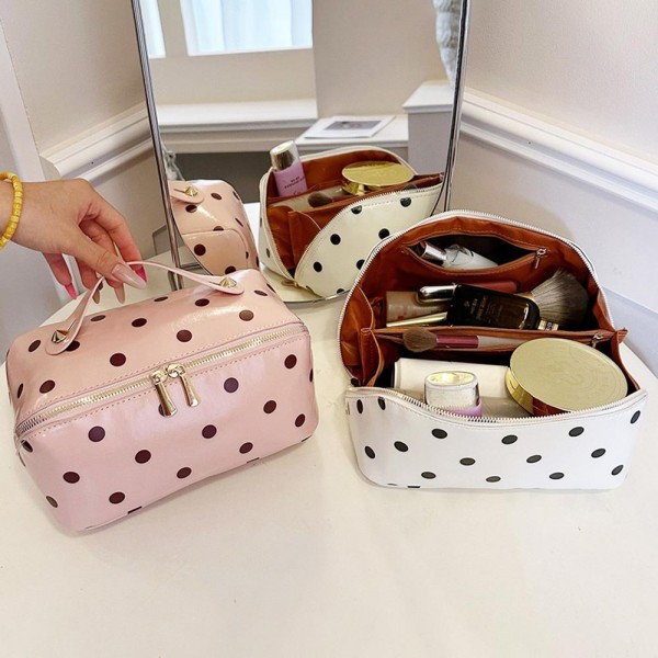 Wide opening makeup case that unzips almost fully so everything lies flat and visible instead of buried at the bottom. A padded body protects glass bottles and pressed compacts, and the short top handle makes it easy to move from counter to suitcase. The coated polka dot exterior wipes clean with a damp cloth. An everyday travel piece priced for repeat purchase and easy gifting.