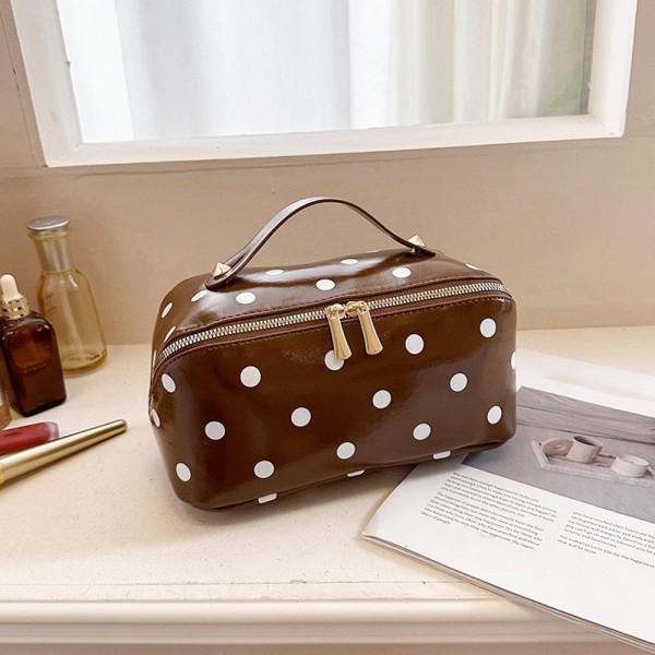 Wide opening makeup case that unzips almost fully so everything lies flat and visible instead of buried at the bottom. A padded body protects glass bottles and pressed compacts, and the short top handle makes it easy to move from counter to suitcase. The coated polka dot exterior wipes clean with a damp cloth. An everyday travel piece priced for repeat purchase and easy gifting.