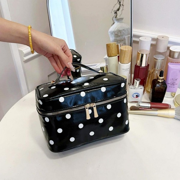 Polka dot vanity case with a wide top zip, a sturdy carry handle, and a boxy shape that opens flat so the whole contents stay in view. The wipe clean lining handles powder spills and sunscreen without staining. Roomy enough for a full routine yet compact enough to live in a weekender bag. It coordinates with the matching totes and pouches for an easy set sale.