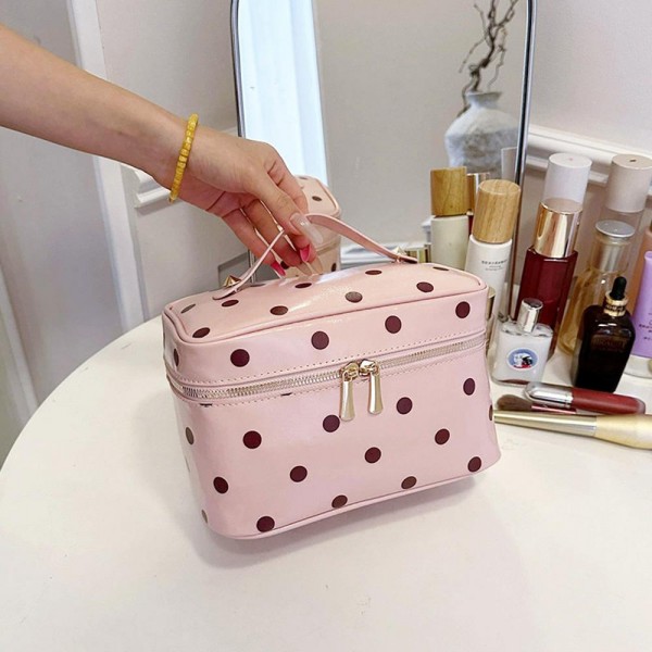 Polka dot vanity case with a wide top zip, a sturdy carry handle, and a boxy shape that opens flat so the whole contents stay in view. The wipe clean lining handles powder spills and sunscreen without staining. Roomy enough for a full routine yet compact enough to live in a weekender bag. It coordinates with the matching totes and pouches for an easy set sale.