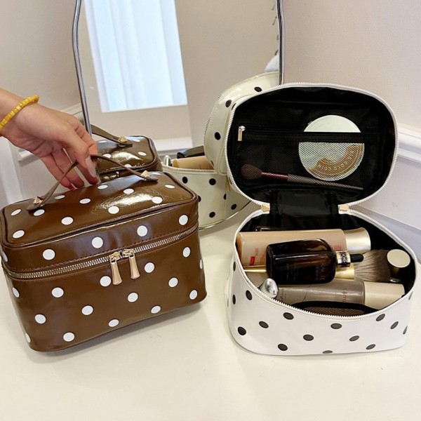Polka dot vanity case with a wide top zip, a sturdy carry handle, and a boxy shape that opens flat so the whole contents stay in view. The wipe clean lining handles powder spills and sunscreen without staining. Roomy enough for a full routine yet compact enough to live in a weekender bag. It coordinates with the matching totes and pouches for an easy set sale.