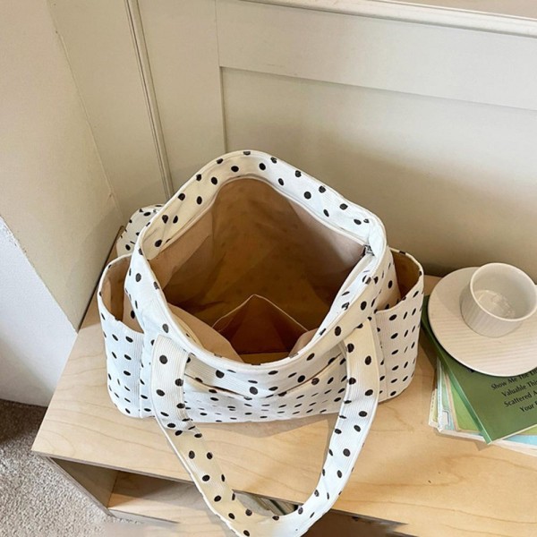 Quilted polka dot tote bag with a roomy main compartment, twin shoulder straps, and open side pockets sized for a phone or a water bottle. The lightweight body holds its shape when packed and folds down flat for storage between trips. A practical everyday carry that covers work, the gym, and weekend errands without looking like a gym bag. Printed totes at this price point move well as an add on beside the register.