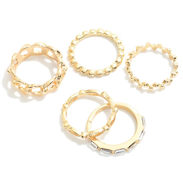 Stackable Ring Set featuring five mixed texture bands, including a chunky chain link ring, a beaded ball band, a scalloped band, a twisted band, and a slim band set with sparkling baguette stones. Wear them all together for a stacked statement or split them across both hands for a lighter look. A versatile everyday set that layers easily with watches and bracelets. Ring sets deliver big value at a small price, making them a dependable impulse buy for boutique jewelry counters.
