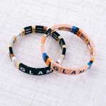 Shiny enamel coated "Glam" letter color block stretch bracelet.

- Approximately 3" in diameter unstretched
- Fits up to a 7" wrist