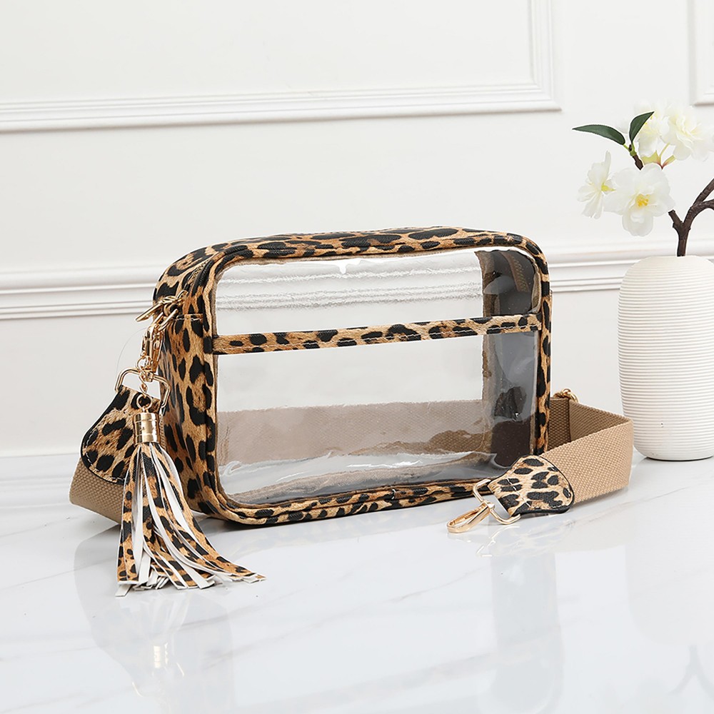 Clear PU Cross Body Bag With Leather Walls and Trim Featuring Detachable Leather Tassel - Zip Closure - One Outer Open Pocket - Detachable Canvas Strap - Approximately 6.5" T x 10" L x 2.5" W - Strap Drop 15" - 24" L view 2